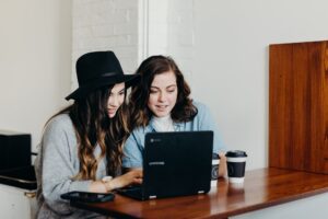 two women look at laptop in cafe