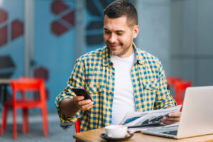 Man logging into his online broker account after reading the newspaper and MoneySense's "Best online brokers in Canada"