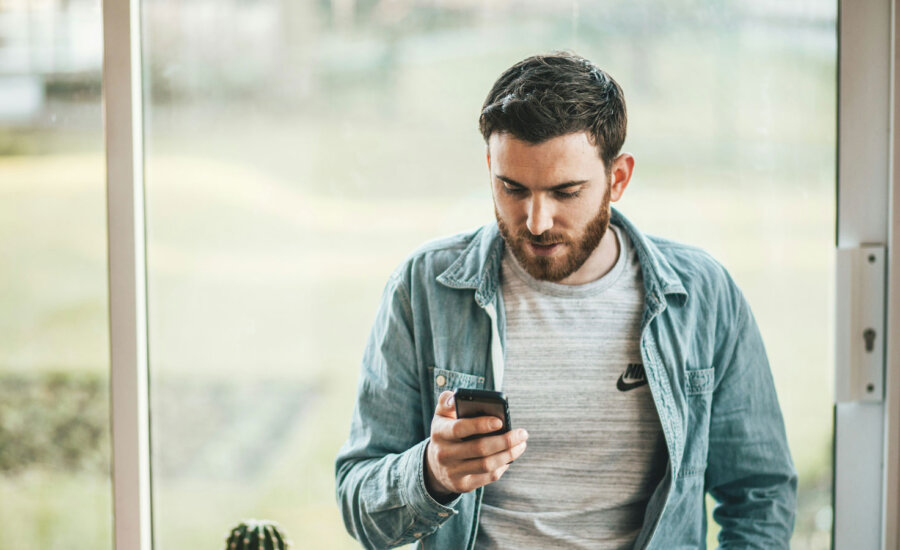 Canadian using his cell phone to check our Best robo-advisors in Canada ranking for 2024.