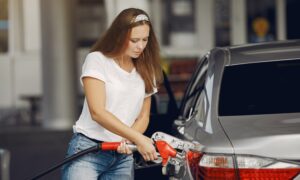 A woman pumps gas into her sedan