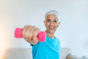 A smiling older woman lifting a small barbell