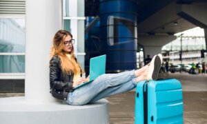 A young woman works on her laptop from the airport