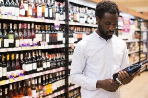 customer inspects wine bottle in liquor store