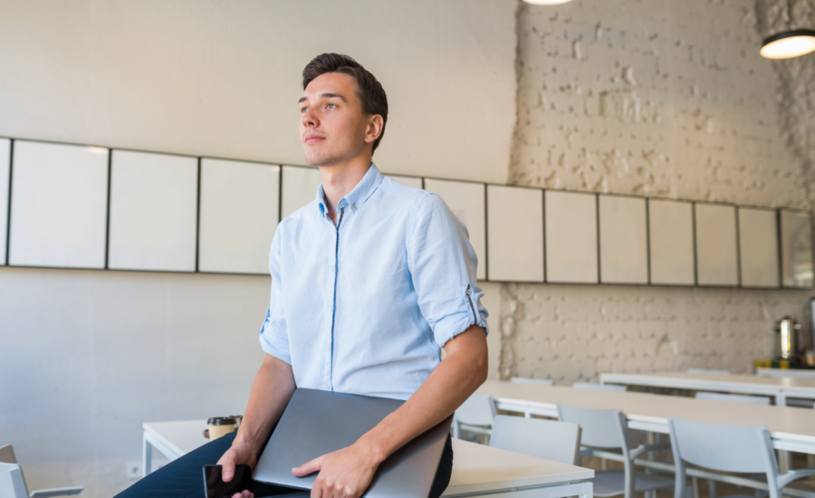 Young man in an office holding a laptop